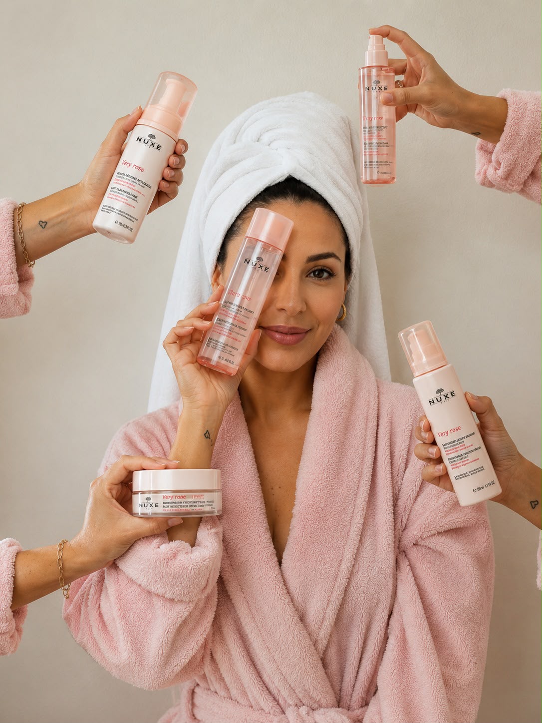 Mulher sorrindo enrolada em roupão, cercada por produtos de beleza em promoção